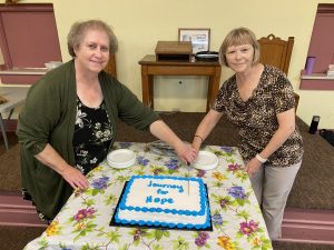 2 ladies cutting a cake